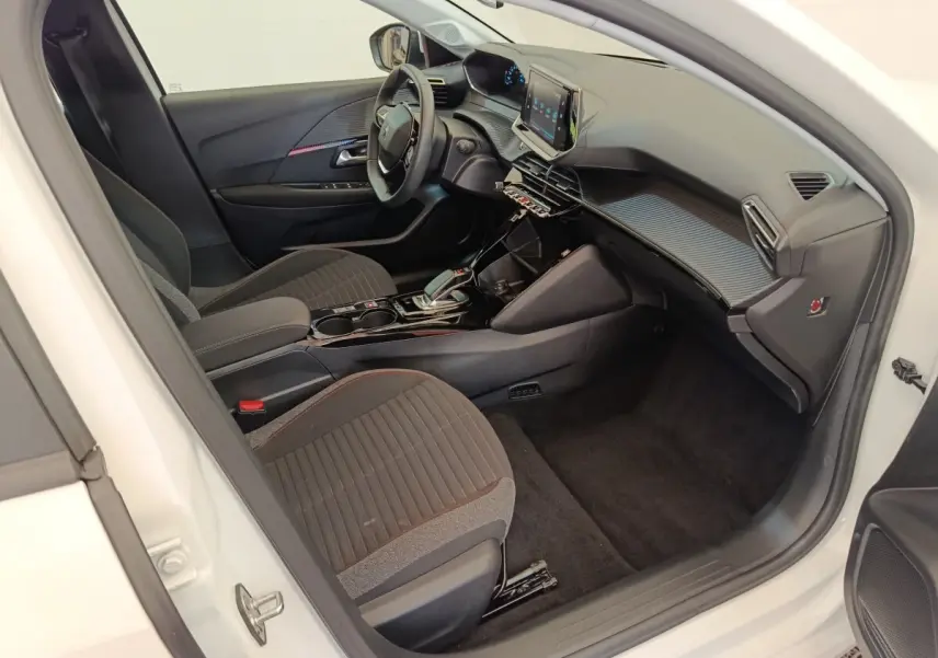 Intérieur côté conducteur de la Peugeot 208 électrique blanche, avec tableau de bord moderne et écran tactile central.
