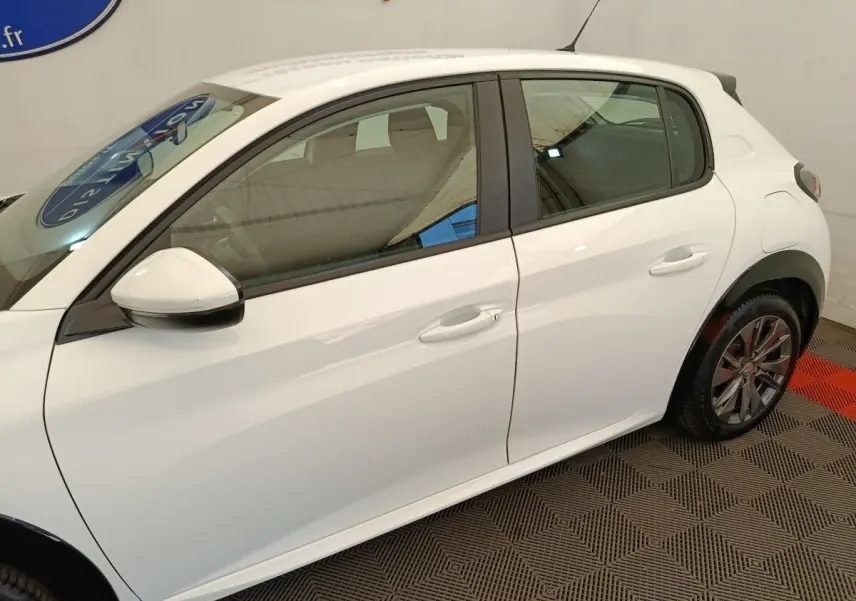 Vue de profil côté gauche d'une Peugeot 208 électrique Active Business R blanche, avec rétroviseur blanc et jantes alliage.