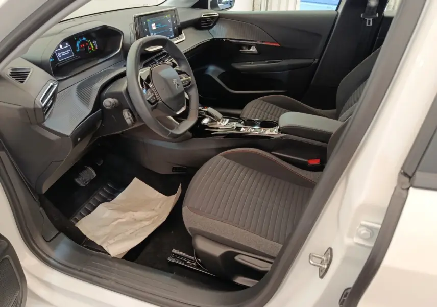 Intérieur côté conducteur de la Peugeot 208 électrique blanche, avec tableau de bord numérique et volant compact multifonctions.
