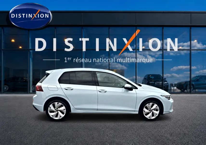 Profil droit d'une Volkswagen Golf 1.5 etsi evo2 116 life dsg7 bleu glacier devant une vitrine Distinxion.