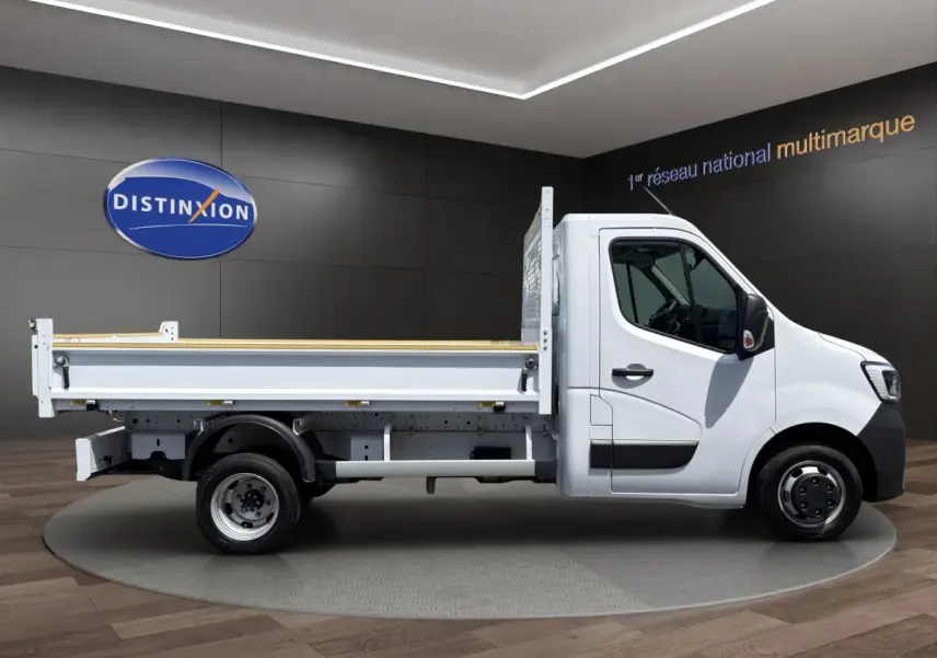 Profil droit d’un utilitaire Renault Master blanc avec benne, jantes acier et cabine simple, en showroom.