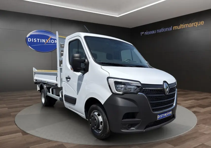 Renault Master blanc en 3/4 avant droit avec benne, calandre noire et jantes acier dans showroom.