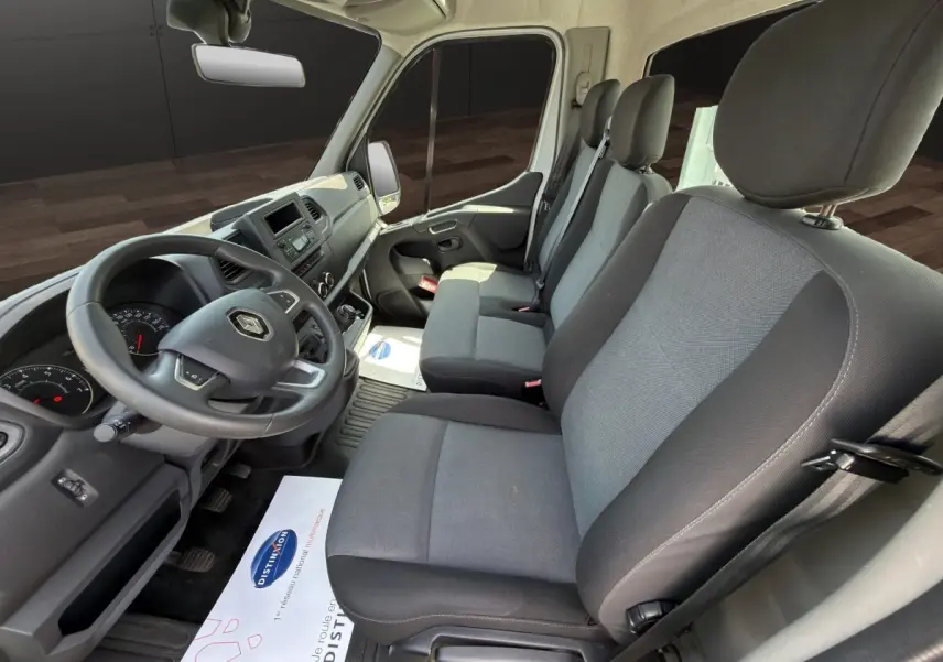 Vue intérieure côté conducteur du Renault Master 2024, sièges gris et tableau de bord noir avec volant réglable.
