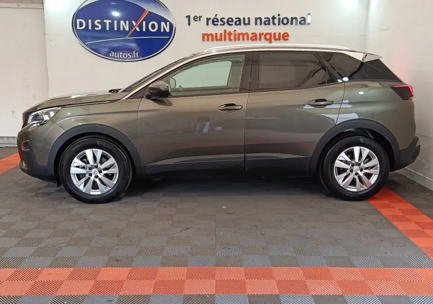 Profil côté gauche d'un Peugeot 3008 gris foncé de 2020 garé en intérieur avec jantes alliage et vitres teintées.