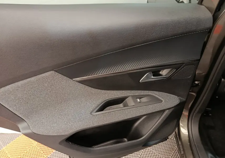 Gros plan sur la porte arrière droite grise du Peugeot 3008 2020, avec garniture tissu et insert effet carbone.
