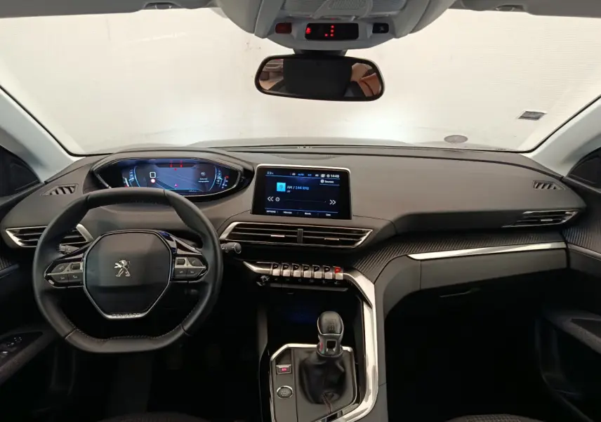 Vue intérieure avant du Peugeot 3008 gris foncé 2020, tableau de bord moderne avec écran tactile et volant multifonctions cuir.