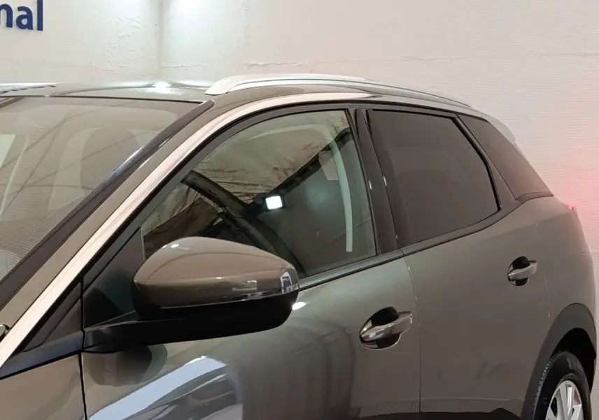 Vue latérale côté gauche d'un Peugeot 3008 gris foncé avec rétroviseur et poignées de porte visibles.