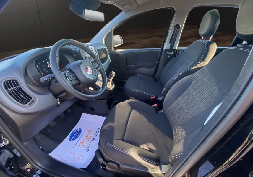 Intérieur avant droit de la Fiat Panda noire 2025, sièges tissu noir et tableau de bord avec écran multimédia.