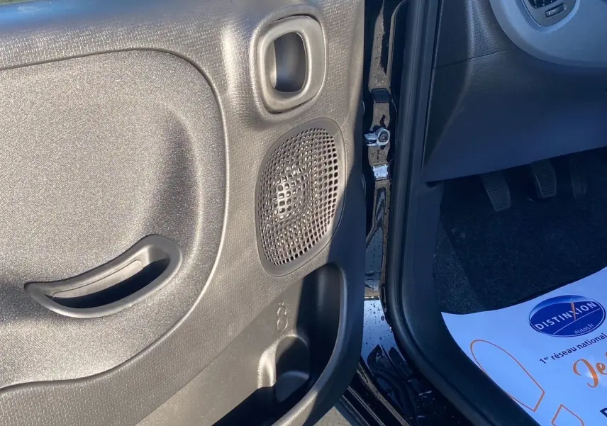 Gros plan sur la porte avant gauche noire de la Fiat Panda 2025, montrant le haut-parleur et la poignée intérieure.