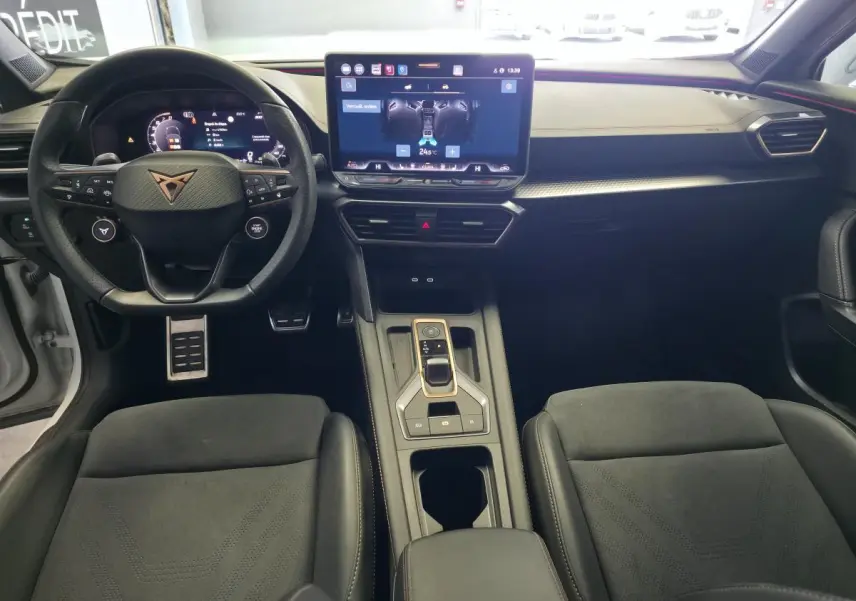 Vue intérieure avant du CUPRA Formentor 1.5 eTSI Hybrid 2025, tableau de bord noir avec écran tactile central et volant sport.
