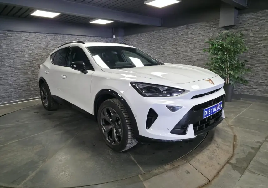 Vue 3/4 avant droite du CUPRA Formentor blanc avec jantes noires et détails noirs contrastants en intérieur showroom.