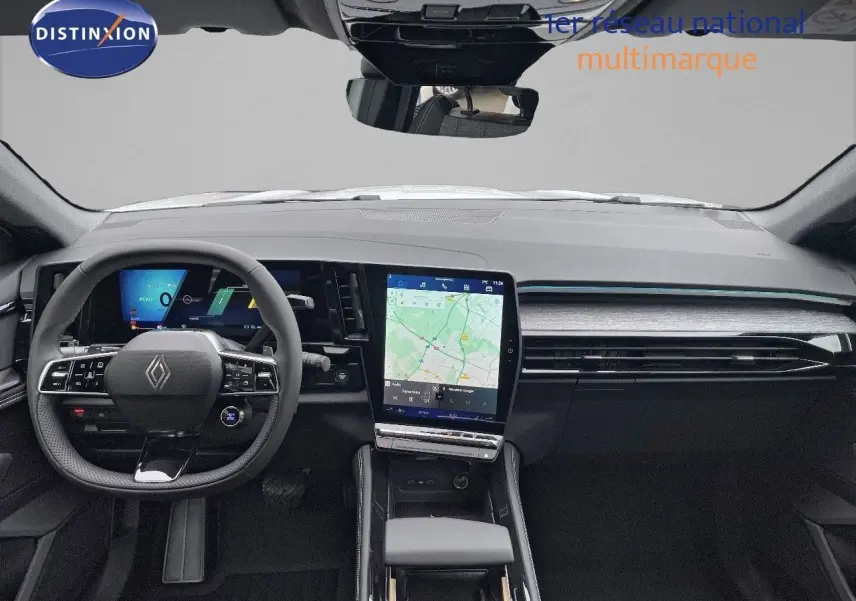 Vue intérieure avant du Renault Austral E-Tech blanc nacré, mettant en valeur le tableau de bord numérique et l'écran tactile central.