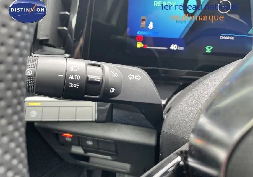 Gros plan sur la commande des feux et clignotants à gauche du volant dans l'habitacle du Renault Austral blanc nacré 2024.