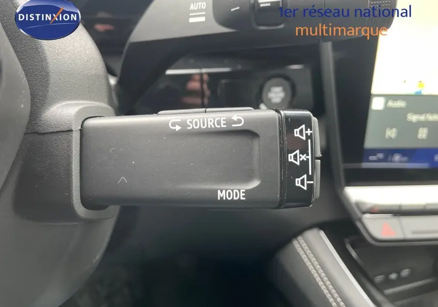 Gros plan sur la commande au volant du Renault Austral blanc nacré 2024, mettant en valeur les fonctions source et mode audio.