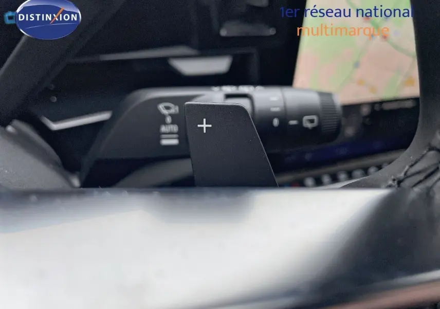 Gros plan sur la palette de changement de vitesse droite du volant du Renault Austral blanc nacré 2024 avec écran tactile en arrière-plan.