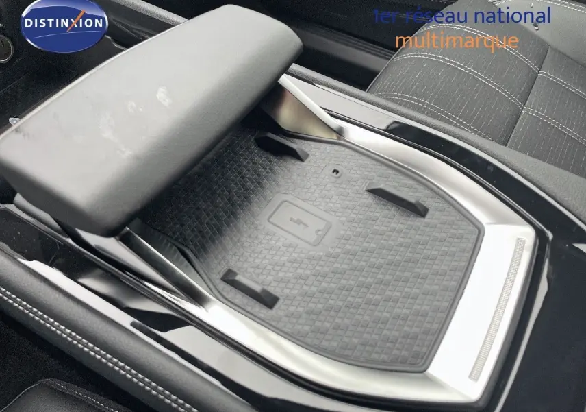 Gros plan sur le chargeur sans fil et l'accoudoir central du Renault Austral E-Tech blanc nacré, intérieur tissu gris.