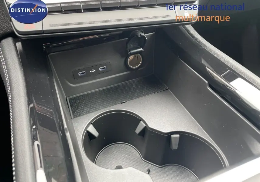 Gros plan sur la console centrale noire du Renault Austral 2024, avec porte-gobelets et prises USB visibles.