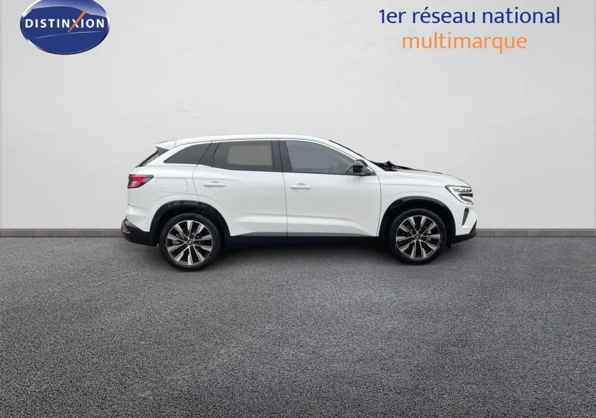 Profil côté droit d'un Renault Austral blanc nacré 2024 hybride, avec jantes bi-ton et lignes épurées.