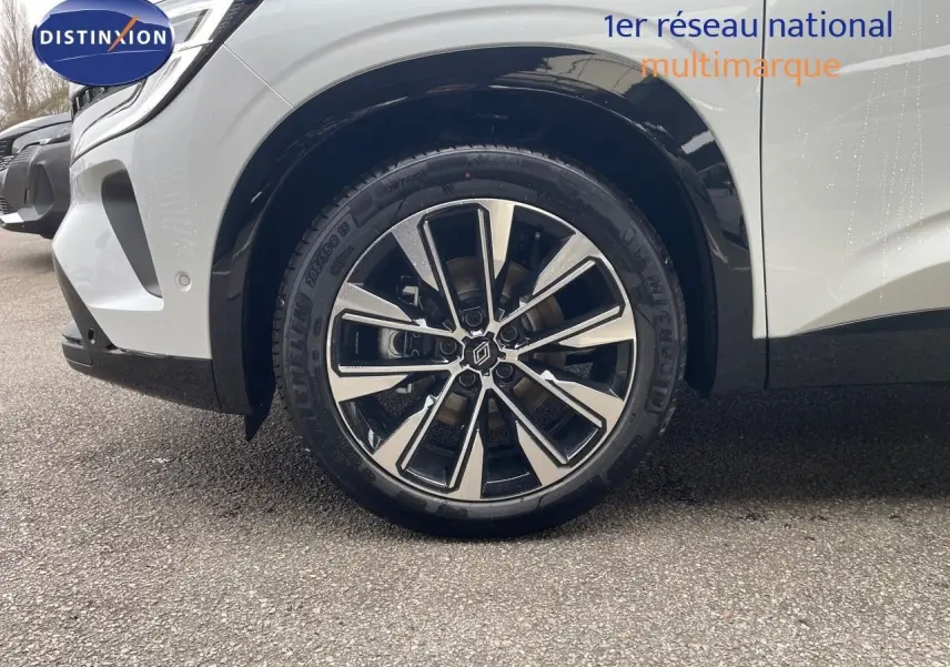 Gros plan sur la roue avant gauche du Renault Austral blanc nacré avec jante bi-ton et logo central Renault.