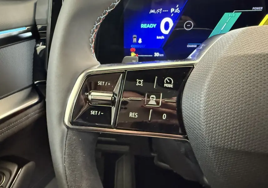 Gros plan sur le volant cuir avec commandes multifonctions et tableau de bord numérique bleu du Renault Espace esprit Alpine 2025.