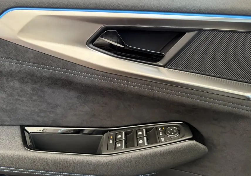 Détail de la porte côté conducteur du Renault Espace gris foncé esprit Alpine 7PL, avec commandes électriques et surpiqûres bleues.