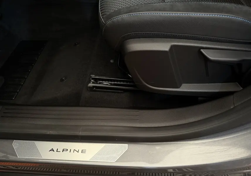 Gros plan sur la porte côté gauche d'un Renault Espace gris foncé esprit Alpine, avec seuil de porte marqué "ALPINE" et siège avant.