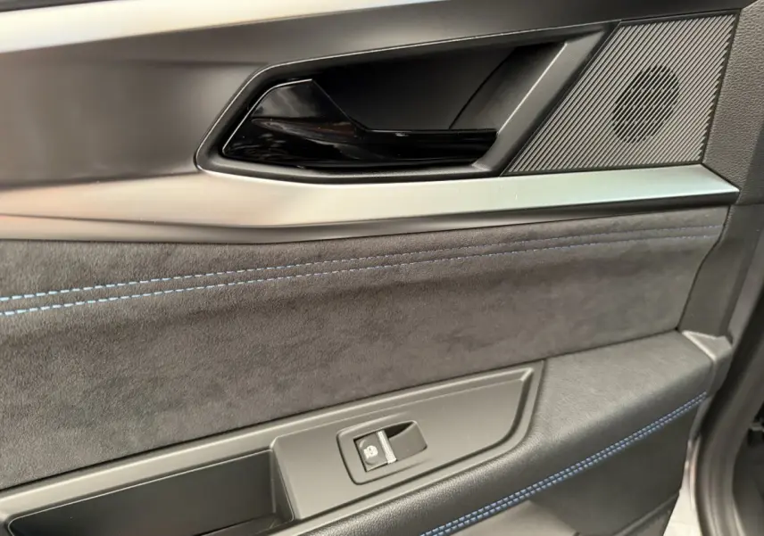 Gros plan sur la garniture intérieure côté droit de porte du Renault Espace gris foncé esprit Alpine avec surpiqûres bleues.