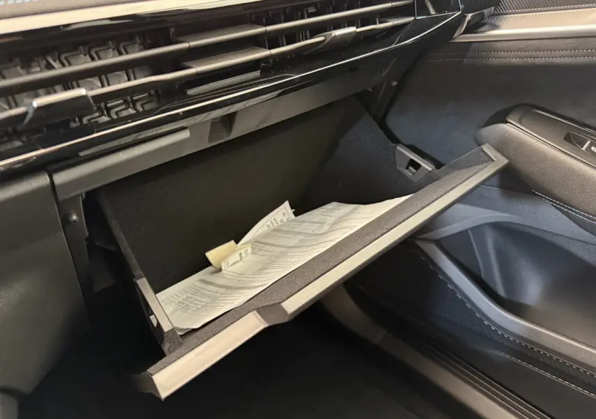 Gros plan sur la boîte à gants ouverte côté passager du Renault Espace gris foncé esprit Alpine 2025 avec documents à l'intérieur.