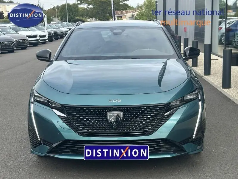 Vue frontale d'une Peugeot 308 SW 2023 vert métallisé avec calandre noire et feux LED verticaux distinctifs.