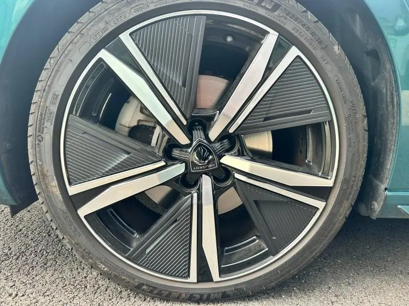 Gros plan sur la jante alu noire et argentée d'une Peugeot 308 SW 2023 bleu vert visible côté gauche.