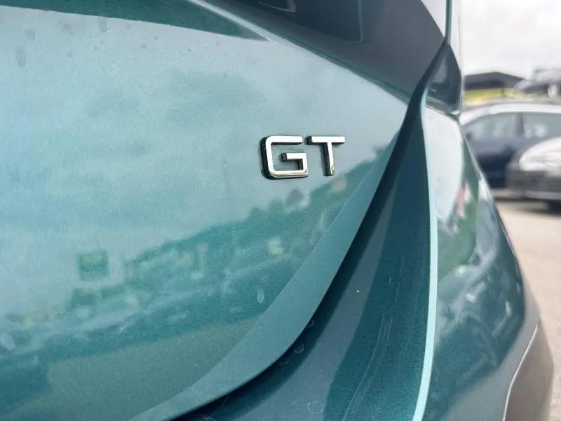 Gros plan sur l'emblème GT à l'arrière d'une Peugeot 308 SW bleu métallisé sous lumière naturelle.