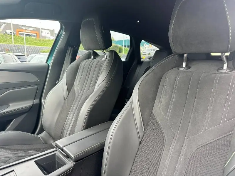 Intérieur de la Peugeot 308 SW 2023 montrant les sièges avant en tissu et cuir noir avec accoudoir central.