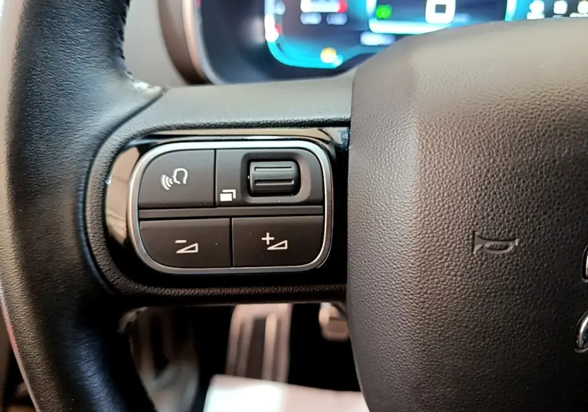 Gros plan sur les commandes multifonctions gauche du volant cuir noir du Citroën C5 Aircross 2020.