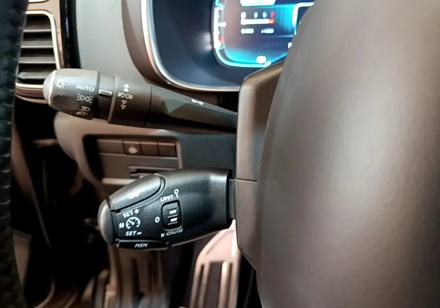 Gros plan sur les commandes du régulateur de vitesse et des feux, volant cuir gris foncé de Citroën C5 Aircross.