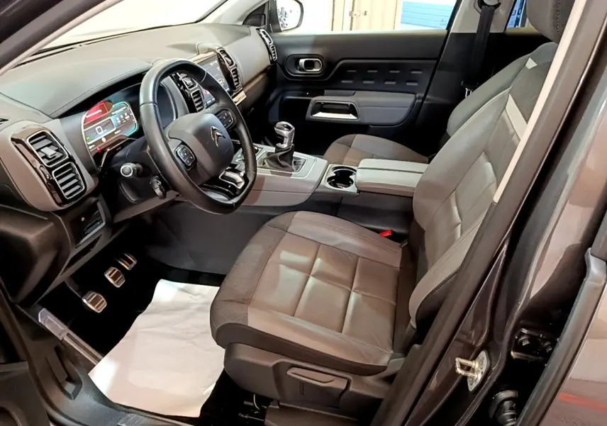 Vue intérieure côté conducteur du Citroën C5 Aircross gris foncé, avec volant cuir multifonctions et tableau de bord digital.