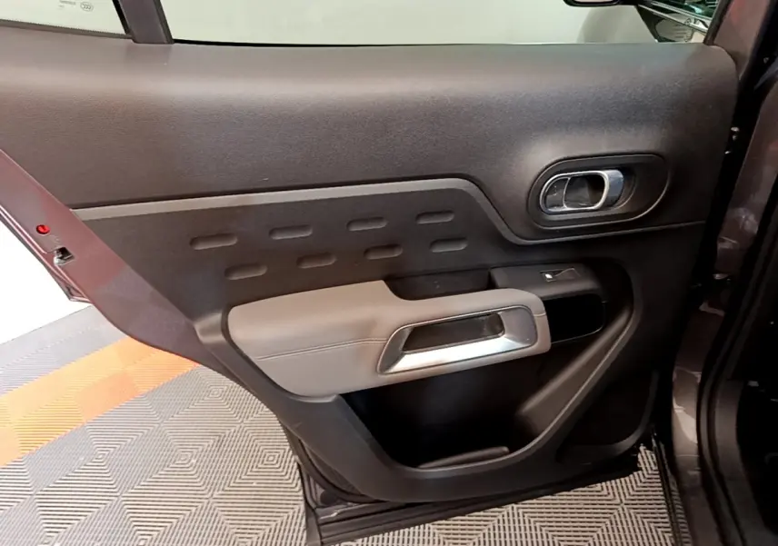 Vue intérieure de la porte arrière droite gris foncé du Citroën C5 Aircross avec poignée argentée et bouton de vitre électrique.