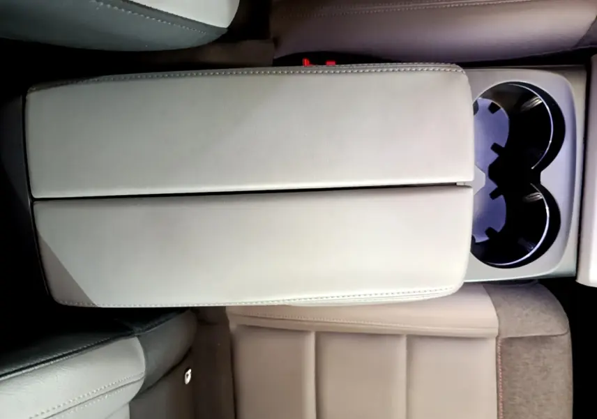 Vue plongeante sur l'accoudoir central beige et les porte-gobelets du siège arrière du Citroën C5 Aircross gris foncé.