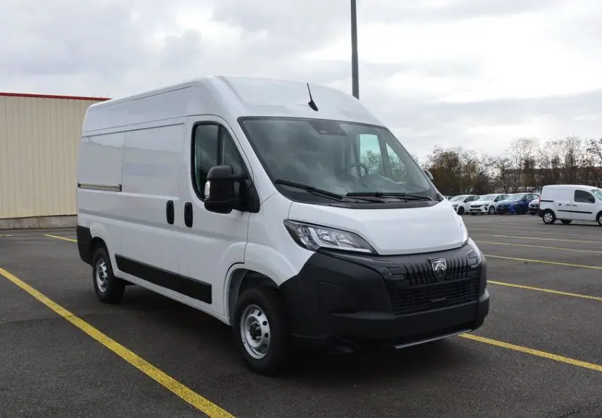 Peugeot Boxer Fourgon blanc Icy vu en 3/4 avant droit sur parking, avec calandre noire et rétroviseurs noirs.