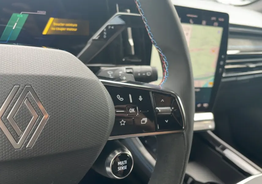 Gros plan sur le volant cuir multifonctions avec surpiqûres bleues du Renault Austral New 200 Esprit Alpine, intérieur moderne.