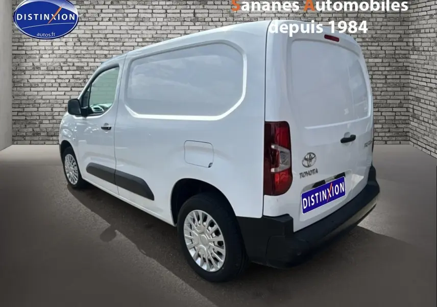 Vue 3/4 arrière droite d'un Toyota Proace City blanc 2023 avec porte latérale tôlée et coques de rétroviseurs noires.