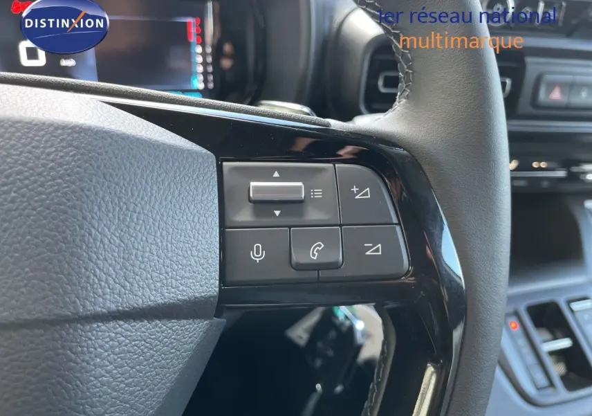 Gros plan sur le volant noir cuir du Citroën Berlingo 2026, avec commandes intégrées et tableau de bord en arrière-plan flou.
