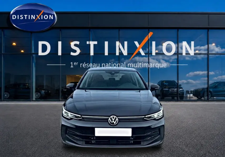 Vue frontale d'une Volkswagen Golf noire 2026 garée devant une vitrine avec logo Distinxion.