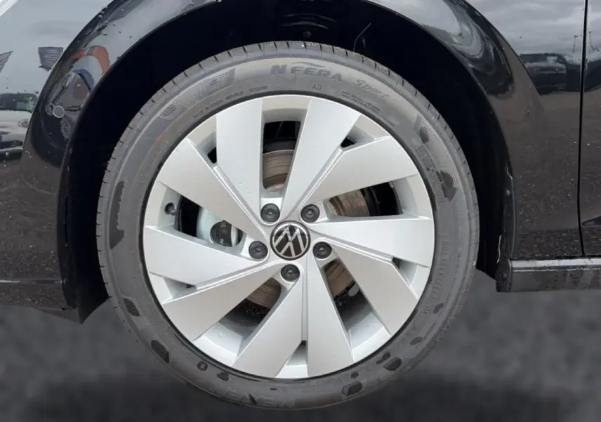 Gros plan sur la roue avant droite d'une Volkswagen Golf noire avec jante alu 17 pouces au design moderne.