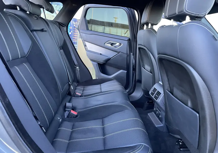 Vue intérieure côté gauche des sièges arrière en cuir noir avec surpiqûres blanches d'un Range Rover Velar gris Corris 2018.