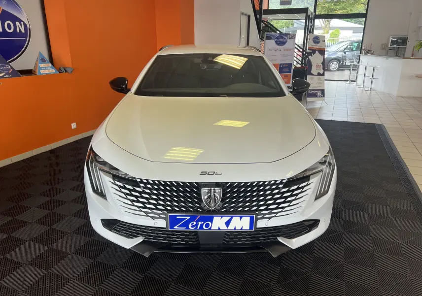 Vue frontale d'une Peugeot 508 SW blanche avec calandre distinctive et logo lion en concession.