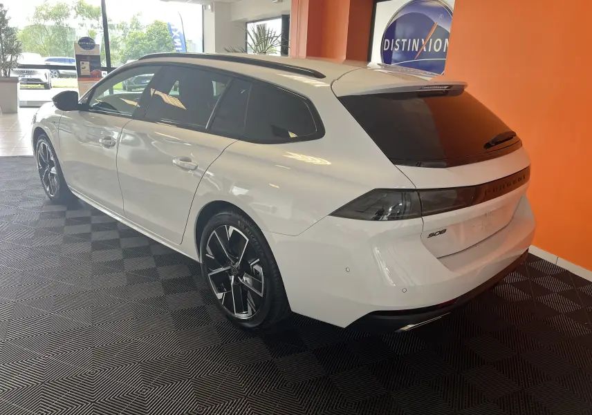 Peugeot 508 SW blanche vue en 3/4 arrière droit, avec vitres teintées et jantes noires bicolores.