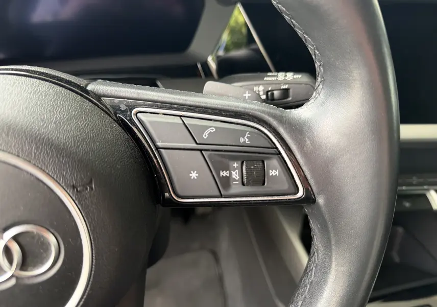 Gros plan sur les commandes à droite du volant en cuir noir de l'Audi A3 Sportback 2021, finition Design, intérieur moderne.