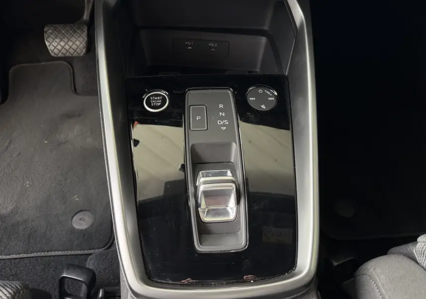 Vue rapprochée de la console centrale noire brillante de l'Audi A3 Sportback 35 TDI avec sélecteur de boîte auto et bouton start/stop.