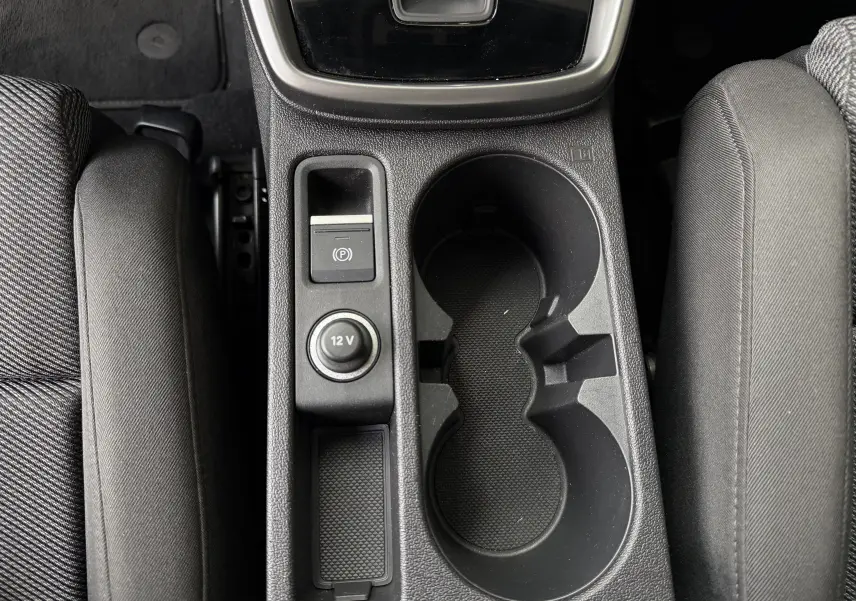 Vue plongeante sur la console centrale noire de l'Audi A3 Sportback, avec porte-gobelets et prise 12V visible entre les sièges avant.
