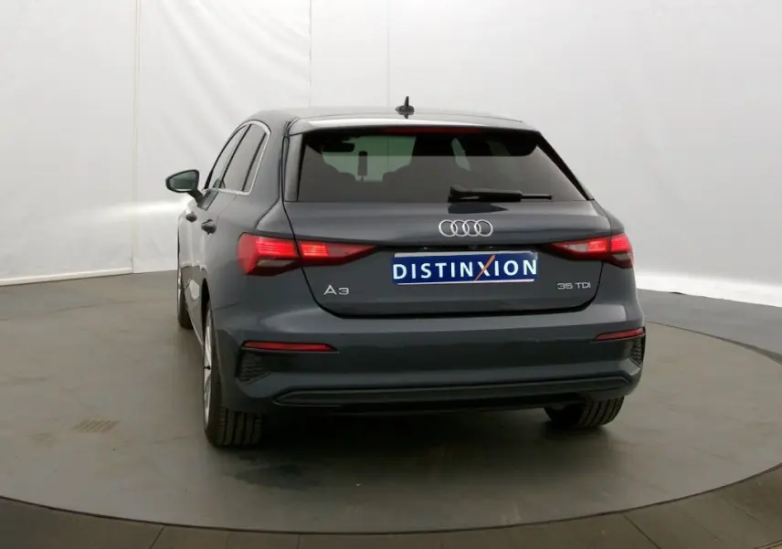 Vue arrière d'une Audi A3 Sportback 35 TDI gris Manhattan de 2021 avec feux arrière allumés dans un studio.
